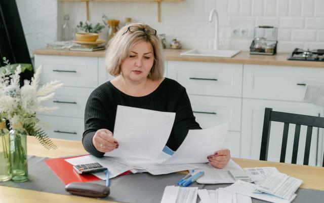 Frau sitzt am Küchentisch und studiert ihre gesammelten Rechnungen und Belege für die Steuer, um von der Fortbildungskosten Pauschale zu profitieren.