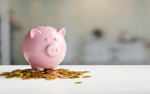 Weiterbildungsprämie: Ein rosafarbenes Schweinchen steht auf dem Tisch, um es herum ein kleiner Haufen an Münzen.